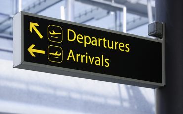 Sign pointing the way to Departures and Arrivals at an airport.